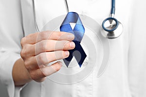 Doctor holding blue awareness ribbon. Symbol of medical issues
