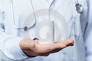 Doctor holding bottle of pills on white background. The concept of medicine, pharmacology, healthcare