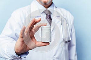 Doctor holding bottle of pills on white background. The concept of medicine, pharmacology, healthcare