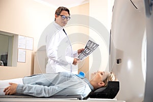 Doctor holding brain CT scan and looking at woman