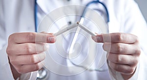 Doctor holding broken cigarette. Stop smoking