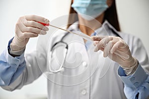 Doctor holding buccal cotton swab and tube for DNA test in clinic, closeup