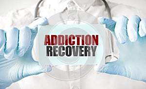 Doctor holding card in hands and pointing the word ADDICTION RECOVERY