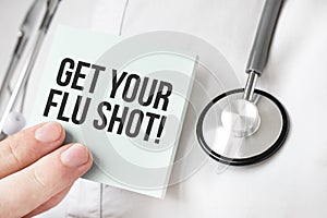 Doctor holding card in hands and pointing the word GET YOUR FLU SHOT
