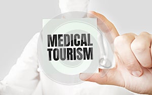 Doctor holding card in hands and pointing the word MEDICAL TOURSIM photo