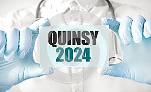Doctor holding card in hands and pointing the word QUINSY 2024