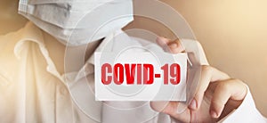 Doctor holding a card with text COVID-19 , medical healthcare concept