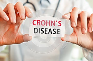 Doctor holding a card with text CROHNS DISEASE in hands. Medical concept photo