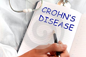 Doctor holding a card with text CROHNS DISEASE, medical concept photo