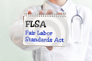 Doctor holding a card with text FLSA Fair Labor Standards Act medical concept