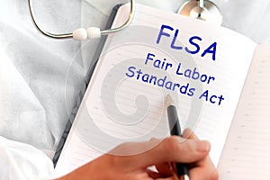 Doctor holding a card with text FLSA, medical concept