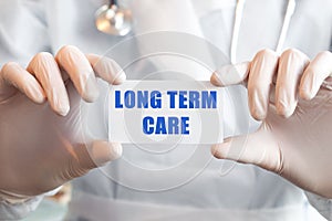 Doctor holding a card with text LONG TERM CARE, medical concept photo