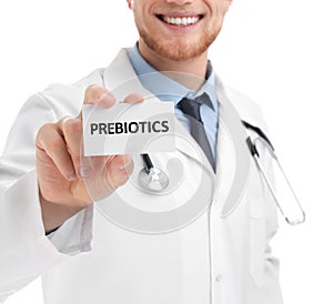 Doctor holding card with word PREBIOTICS on white background, closeup photo