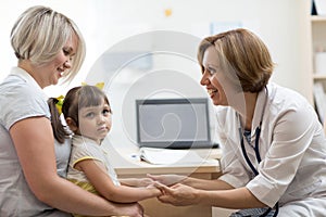 Doctor holding child hand with care in hospital. Healthcare, childhood and medicine concepts.