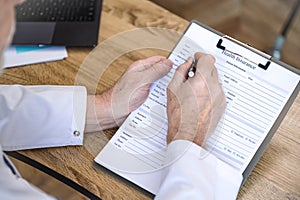 Doctor holding clipboard, filling out patient medical information