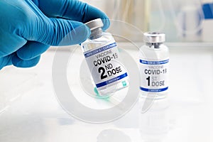 Doctor holding Coronavirus vaccine vial with the name of second dose of the vaccine on the label