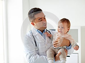 Doctor holding crying baby at clinic