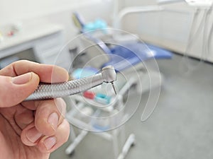 doctor is holding a dental turbine handpiece for dental treatment.