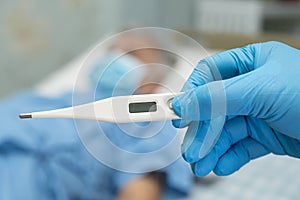 Doctor holding digital thermometer to measures asian elderly woman patient wearing a face mask have a fever in hospital, healthy