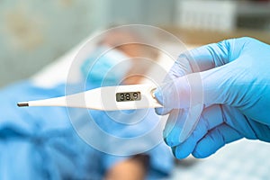 Doctor holding digital thermometer to measures asian senior or elderly old lady woman patient