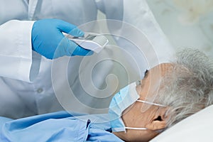 Doctor holding digital thermometer to measures asian senior or elderly old lady woman patient wearing a face mask have a fever