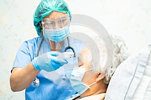 Doctor holding digital thermometer to measures asian senior or elderly old lady woman patient wearing a face mask have a fever in