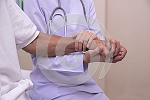 Doctor holding elderly patient`s hands with care