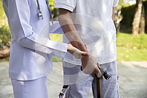 Doctor holding elderly patient`s hands with walking stick