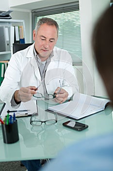 Doctor holding glasses and talking to patient