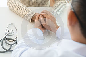 Doctor holding hands and encouraging depressed female patient to fight.