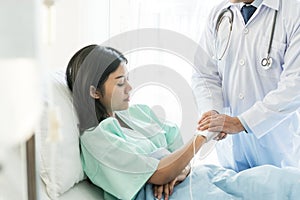 Doctor holding hands and encouraging depressed female patient to fight with cancer on the bed.