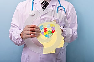 Doctor holding head with jigsaw puzzle brain shape - Autism spectrum disorder concept photo