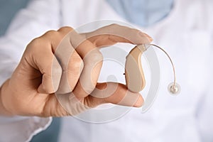 Doctor holding hearing aid, closeup