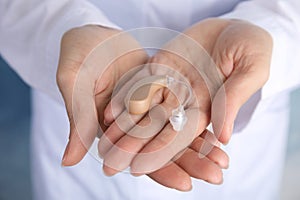 Doctor holding hearing aid, closeup
