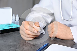 Doctor holding hearing aid at table, closeup