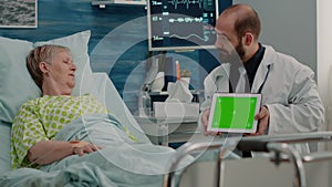 Doctor holding horizontal green screen on digital tablet