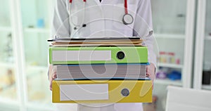 Doctor is holding large stack of folders and medical documents