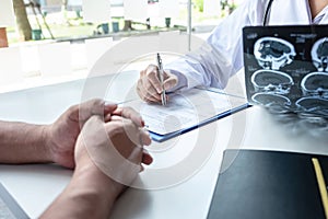 Doctor holding and looking at x-ray film examining at brain by ct scan of patient and analyze result while discussing explaining