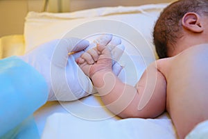 Doctor holding newborn child`s hand in hospital