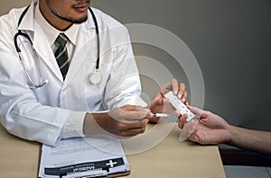 Doctor Holding pack of tablet blisters in hand  in front of patient and reviewing his medication