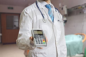 Doctor is holding payment terminal in hands. Paying for health care