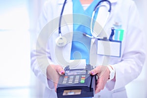 Doctor is holding payment terminal in hands. Paying for health care. Doctor