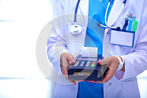 Doctor is holding payment terminal in hands. Paying for health care. Doctor