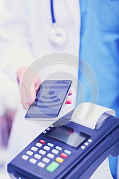 Doctor is holding payment terminal in hands. Paying for health care. Doctor