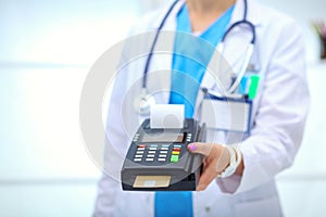 Doctor is holding payment terminal in hands. Paying for health care. Doctor