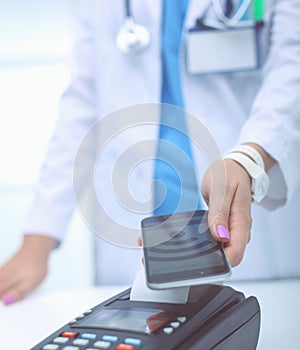 Doctor is holding payment terminal in hands. Paying for health care. Doctor