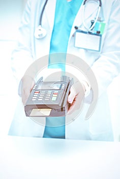 Doctor is holding payment terminal in hands. Paying for health care. Doctor