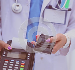 Doctor is holding payment terminal in hands. Paying for health care. Doctor