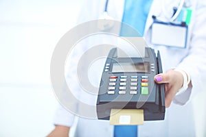 Doctor is holding payment terminal in hands. Paying for health care. Doctor