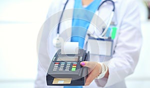 Doctor is holding payment terminal in hands. Paying for health care. Doctor